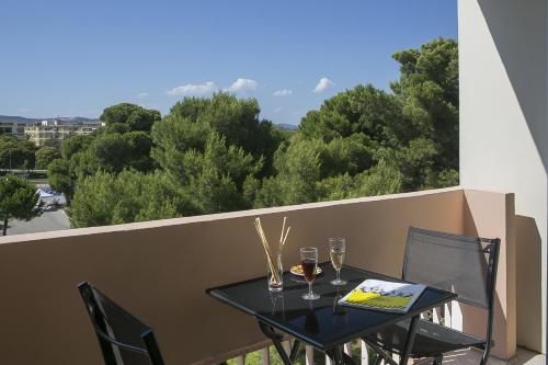 a table with two glasses of wine on a balcony at Best Western Hôtel des Thermes - Balaruc les Bains Sète in Balaruc-les-Bains
