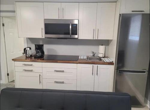 uma cozinha com armários brancos e um frigorífico de aço inoxidável em Private Apartment in Ottawa near the Ottawa hospital em Ottawa