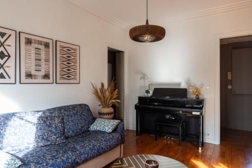 een woonkamer met een bank en een piano bij Charming T3 at the gates of Paris in Clichy