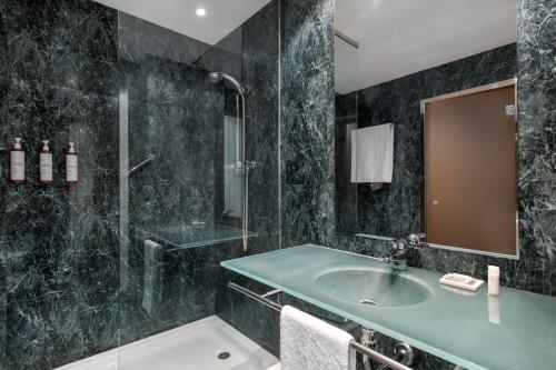 La salle de bains est pourvue d'un lavabo et d'une douche. dans l'établissement AC Hotel León San Antonio by Marriott, à León