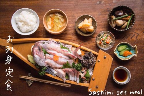 a wooden table with a plate of food on it at Book & Guesthouse Hitotomaru in Toyooka