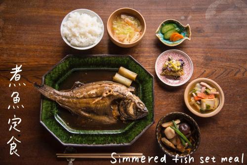 a plate of food with a fish and other dishes at Book & Guesthouse Hitotomaru in Toyooka