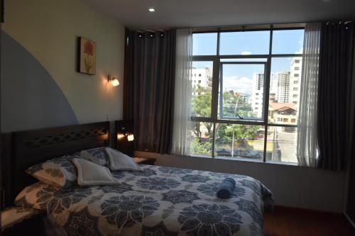 um quarto com uma cama e uma grande janela em Departamento Jerry em Cochabamba