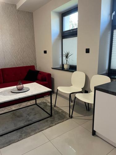 a living room with a red couch and white chairs at Apartamenty na Blichu - Noclegi Energylandia Zator in Zator