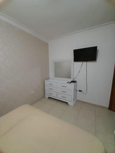 a bedroom with a bed and a flat screen tv at J. B Apartamentos in Santo Domingo