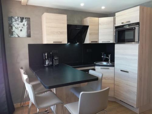 une cuisine avec un comptoir noir et des chaises blanches dans l'établissement Val thorens appartement 2 ch avec belle vue sud, à Val Thorens