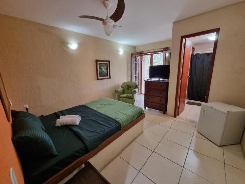 a bedroom with a green bed and a television at Pousada Zênit Peró II in Cabo Frio