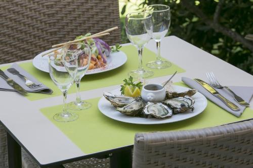 a table with two plates of food and wine glasses at Best Western Hôtel des Thermes - Balaruc les Bains Sète in Balaruc-les-Bains