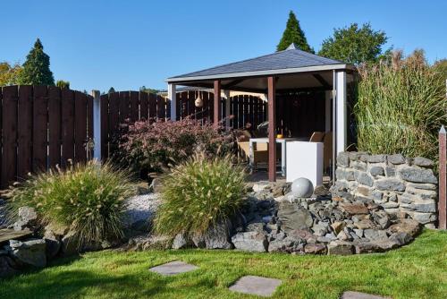 a garden with a gazebo and a stone wall at Ferienwohnung Haaren in Waldfeucht