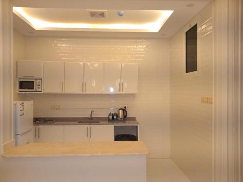 a kitchen with white cabinets and a sink at ضيف بارك للأجنحة الفندقية in Ad Dawādimī