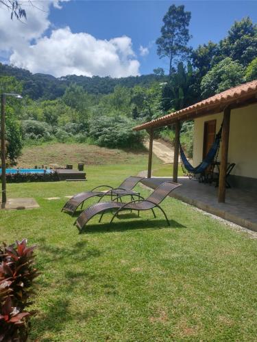 two chairs and a hammock in a yard at Chalé encontro dos rios in Nova Friburgo