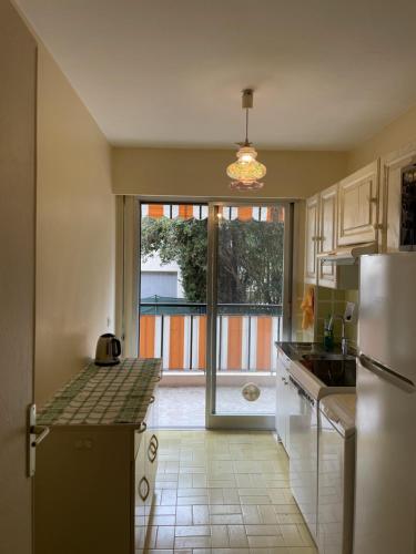 Il comprend une cuisine équipée d'un réfrigérateur et une grande fenêtre. dans l'établissement 2 pièces à 5min de Cannes, au Cannet