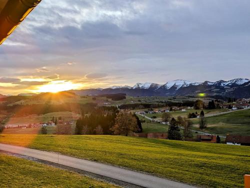 een zonsondergang over een weg met bergen op de achtergrond bij Ferienwohnung Alpenblick Dorner in Oberreute