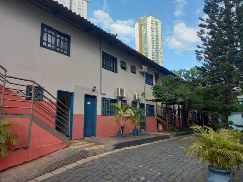 a white building with blue and red doors on a street at Hotel Serras De Goyaz Bueno, Goiânia in Goiânia
