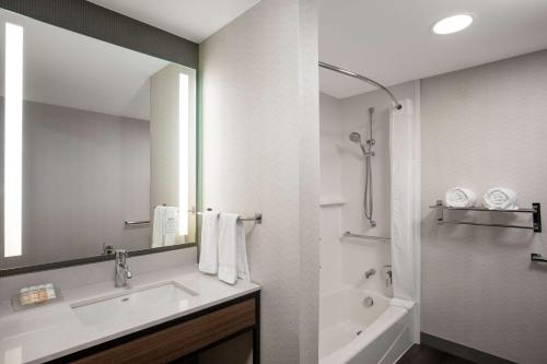 uma casa de banho com um lavatório, uma banheira e um espelho. em Hilton Garden Inn Kalispell em Kalispell