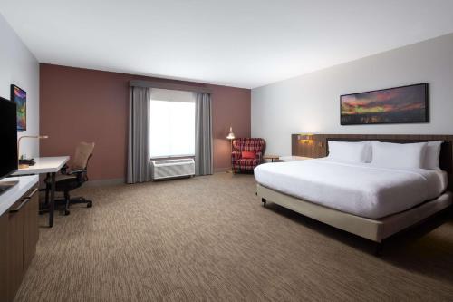 um quarto de hotel com uma cama, uma secretária e uma televisão em Hilton Garden Inn Kalispell em Kalispell