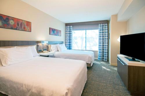 a hotel room with two beds and a flat screen tv at Hilton Garden Inn Jackson/Pearl in Pearl
