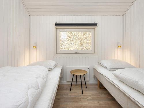 Holiday home Ansager X في Ansager: سريرين في غرفة بيضاء مع نافذة