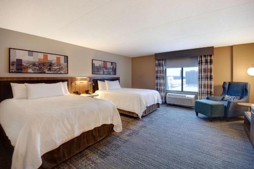 a hotel room with two beds and a chair at Hilton Garden Inn Terre Haute in Terre Haute