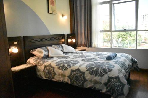 a bedroom with a bed with a comforter and a window at Departamento Jerry in Cochabamba