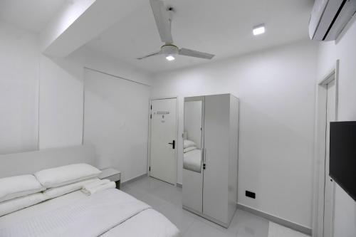 a white bedroom with a bed and a ceiling fan at Seaview Apartment by Lin Residences in Male City