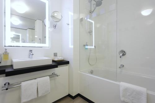 a white bathroom with a shower and a sink at Lindner Hotel Dusseldorf Airport, part of JdV by Hyatt in Düsseldorf