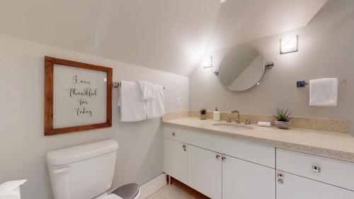 a white bathroom with a toilet and a mirror at 2BR Renovated Townhouse in Benchlands by Harmony Whistler in Whistler