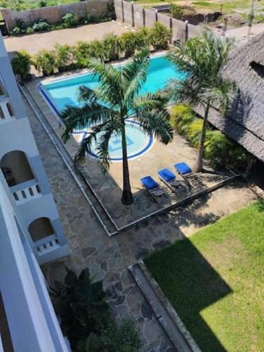 an overhead view of a swimming pool with palm trees and chairs at Nightingale Apartments Hotel Mombasa in Shanzu