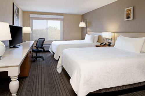 a hotel room with two beds and a desk at Hilton Garden Inn Roseville in Roseville