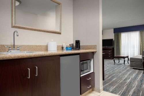 a kitchen with a sink and a living room at Hampton Inn Syracuse Clay in Liverpool
