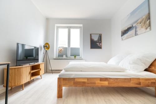 a white bedroom with a bed and a tv at Zentrales Apartment am Nordertor in Flensburg