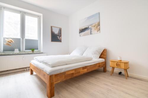 a white bedroom with a bed and a table at Zentrales Apartment am Nordertor in Flensburg