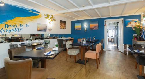 a restaurant with tables and chairs and blue walls at De L'Etang in Saint Helier Jersey