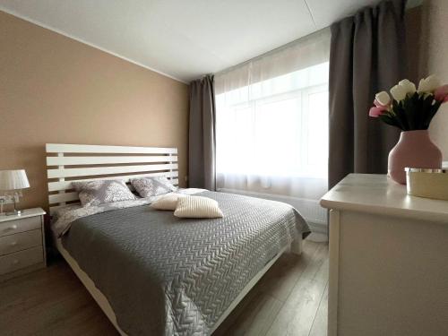 Un dormitorio con una cama con un jarrón de flores. en Pärnu Beach Apartment, en Pärnu