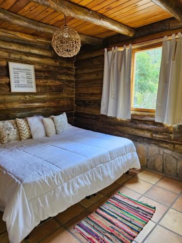ein Schlafzimmer mit einem großen Bett in einem Blockhaus in der Unterkunft Sommerwind Cabañas in La Estancia