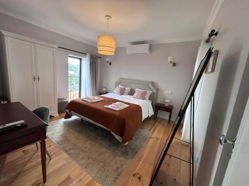 a bedroom with a bed and a desk and a window at Castas do Douro in Tabuaço