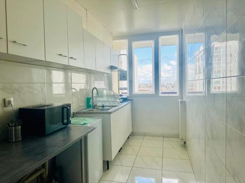une cuisine blanche avec un évier et une fenêtre dans l'établissement paris holiday, à Aubervilliers