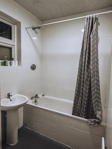 a bathroom with a bath tub and a sink at Spacious 3 rooms in Tooting in London