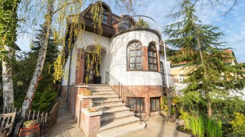 ein großes weißes Haus mit einer Treppe davor in der Unterkunft Villa Butterfly in Budapest