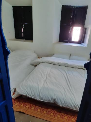 Guest house tassaoute : سريرين في غرفة بها نافذتين