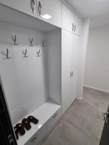 a kitchen with white cabinets and shoes on a shelf at Apartman Panorama Doboj in Doboj