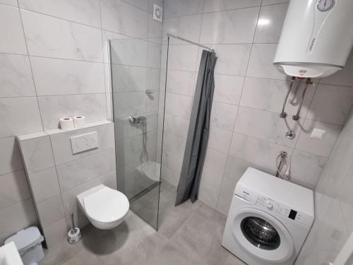 a bathroom with a shower and a toilet and a washing machine at Apartman Panorama Doboj in Doboj