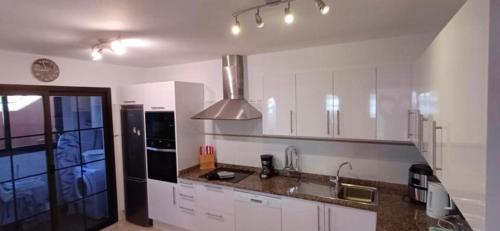 a kitchen with white cabinets and a stainless steel appliances at Villa 20 in Caleta De Fuste