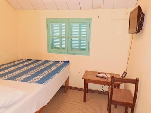 um quarto com uma cama, uma mesa e uma janela em Auberge Mariama BA em Gorée