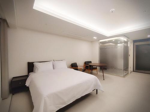 a bedroom with a large white bed and a table at Bluebird Hotel in Incheon