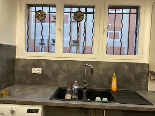 een keukengootsteen met daarboven glas-in-loodramen bij Appartement Amaya 1 - 100 m2 Paris 2024 in Pontoise