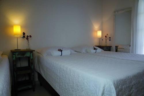 a bedroom with a large white bed and two lamps at Vila dos Caetés - Suíte 05 - Barra do Sahy in Barra do Sahy