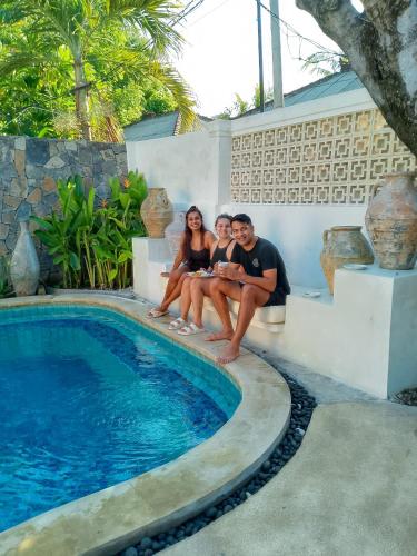 a group of people sitting next to a swimming pool at Gili Breeze Tropical Bungalows in Gili Trawangan