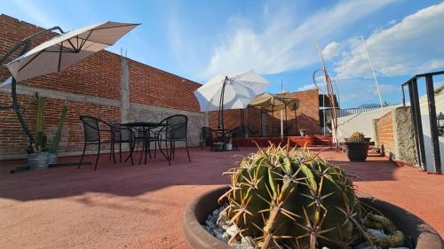 eine Terrasse mit einem Tisch, Stühlen und Sonnenschirmen in der Unterkunft Meraky in Oaxaca de Juárez