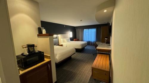 a hotel room with a bedroom with two beds and a desk at Courtyard by Marriott Kingston in Kingston